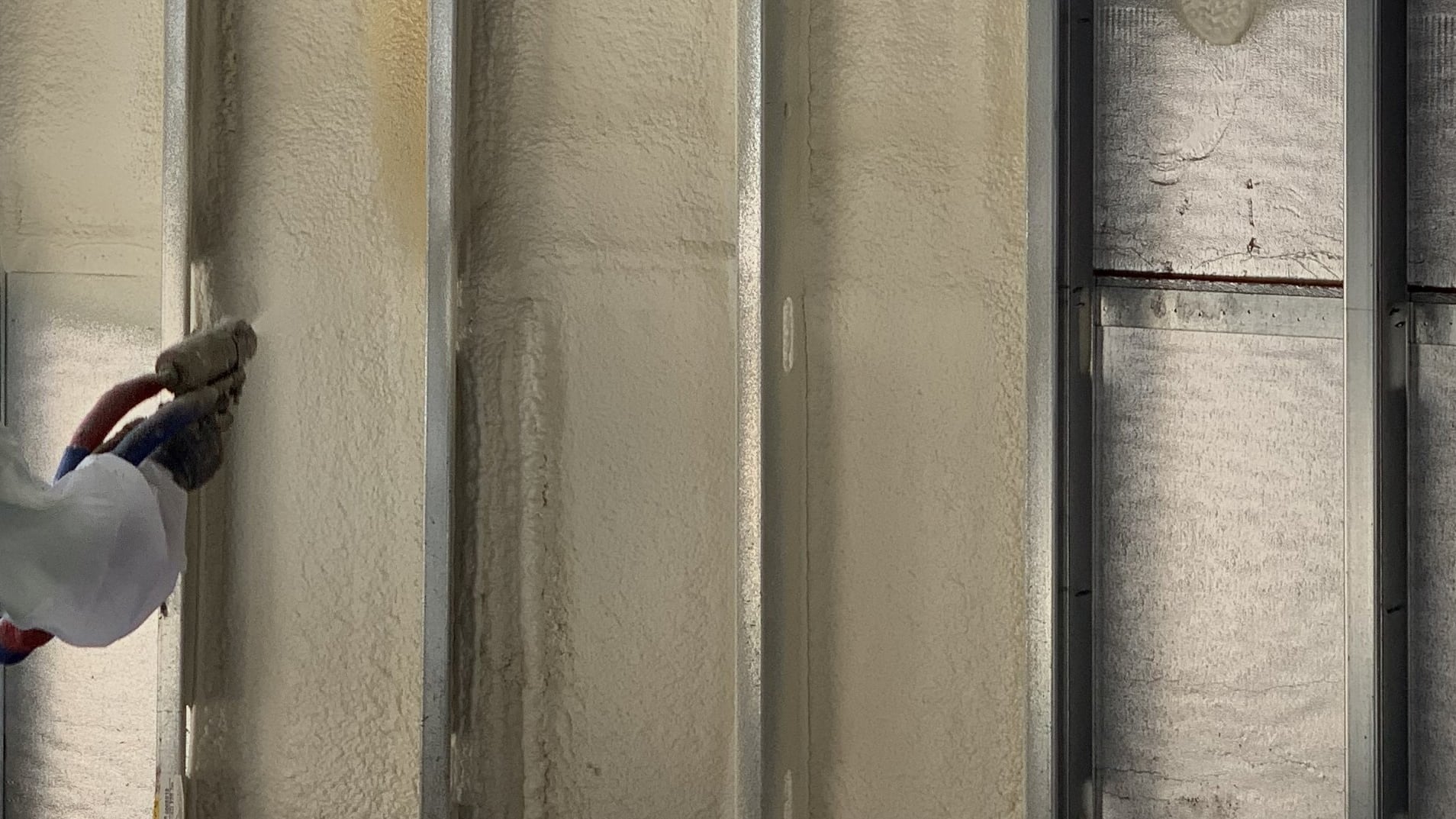 a person applying spray foam insulation to a wall