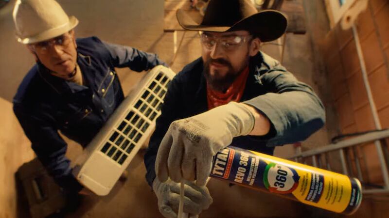 a man in a cowboy hat using a PU foam can on a construction site