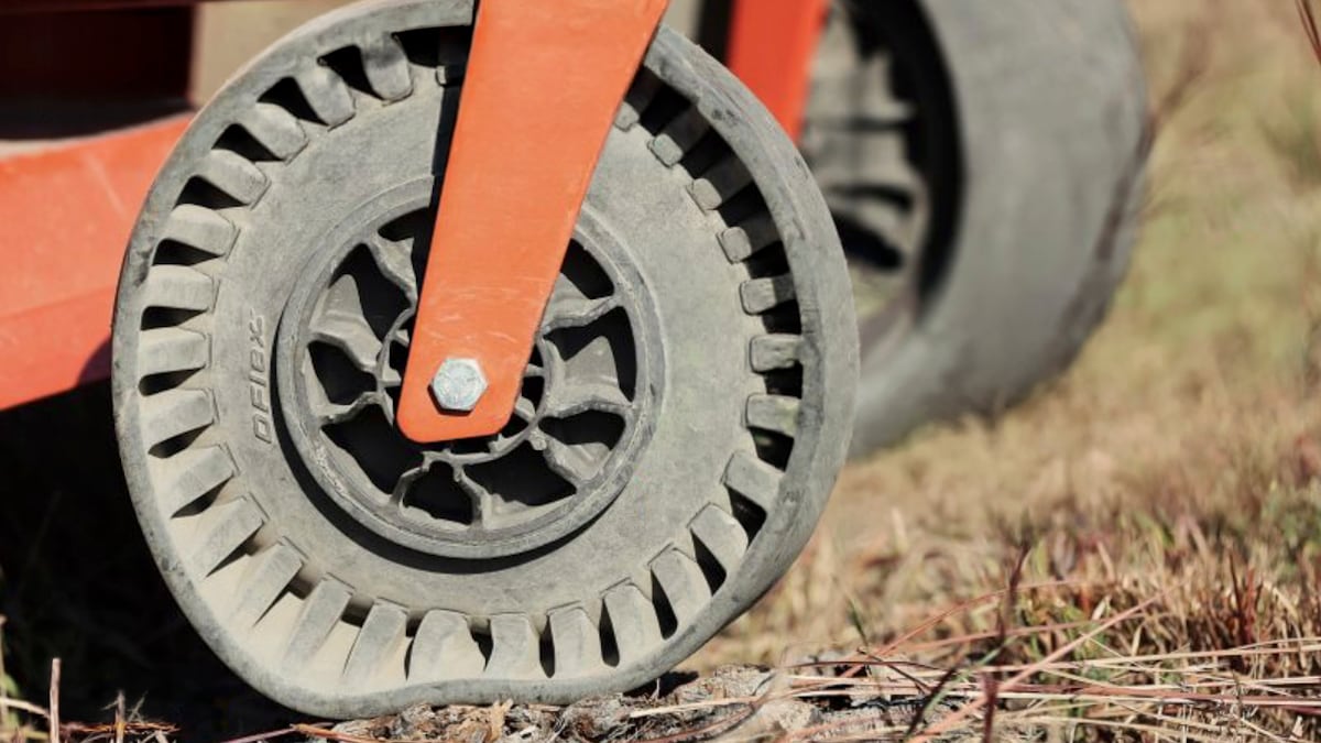 a black wheel on an orange machine deforming on the ground