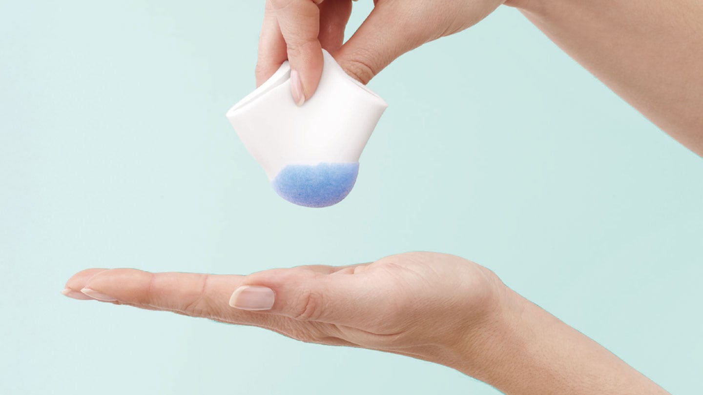 a pair of hands holding a piece of foam full of liquid
