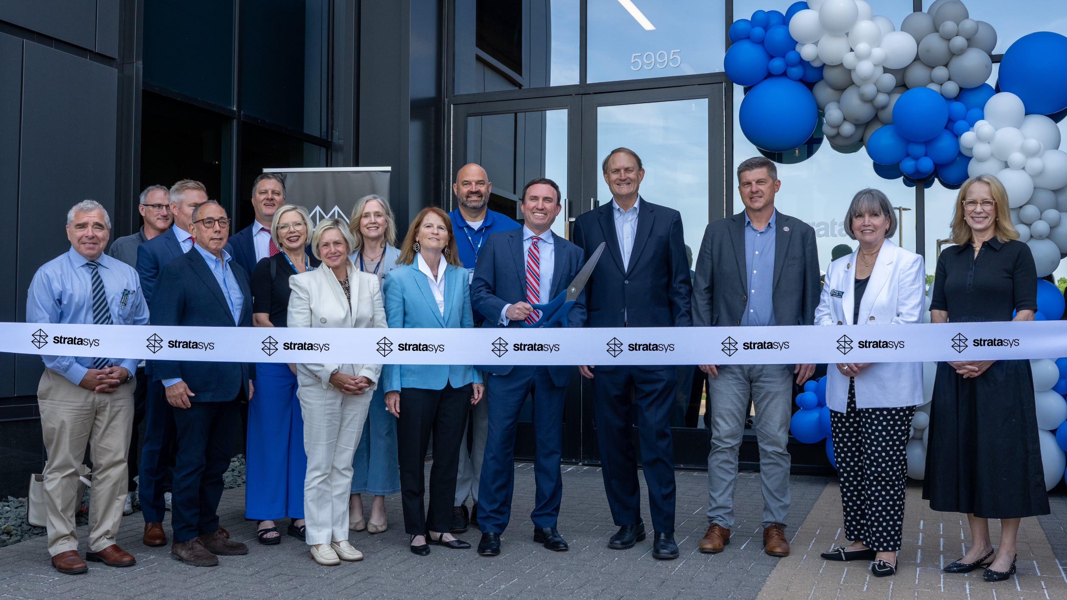a group of people ready to cut a ribbon at an official opening
