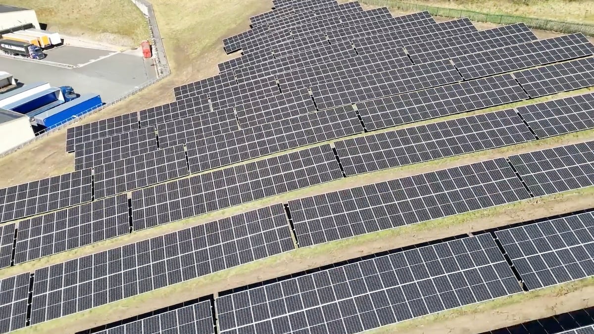 a lot of solar panels on a hillside next to a factory