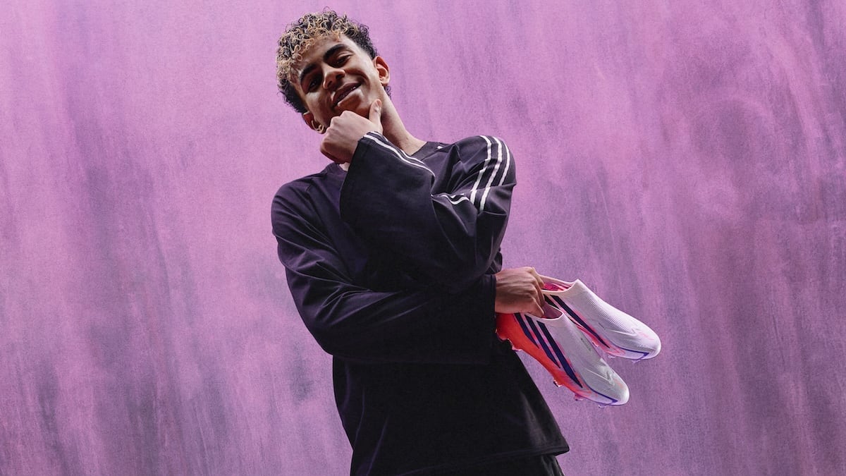 a young footballer holding pink and white football boots