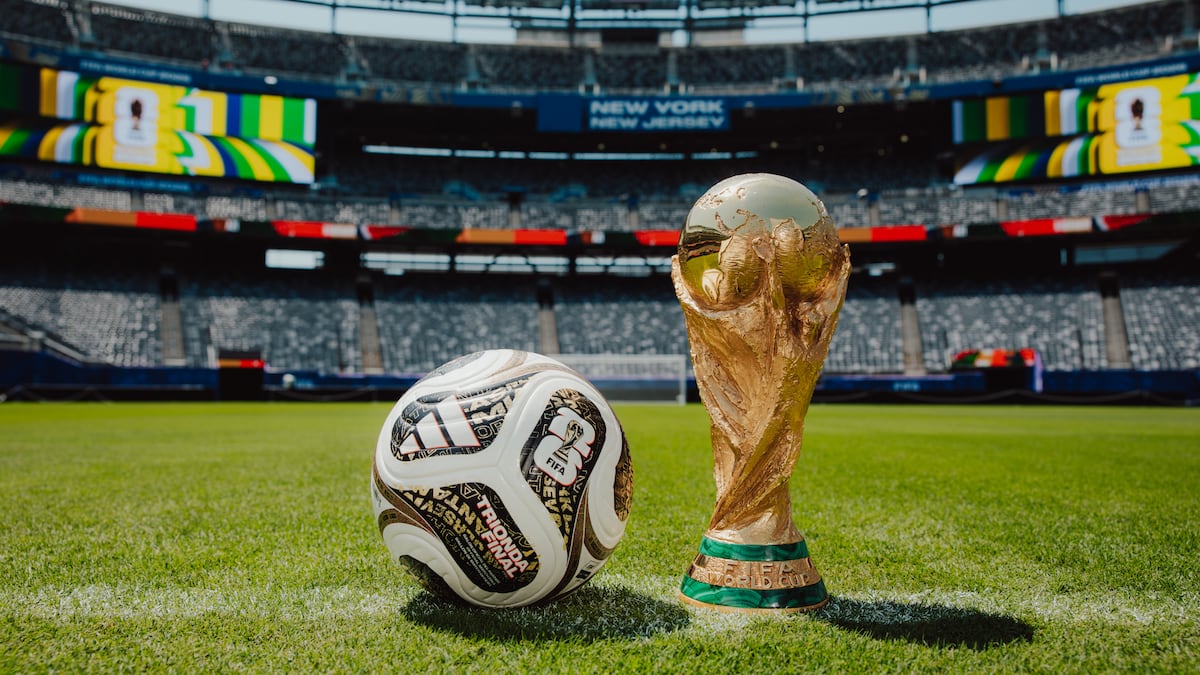 a football and the world cup trophy on the grass in a football stadium