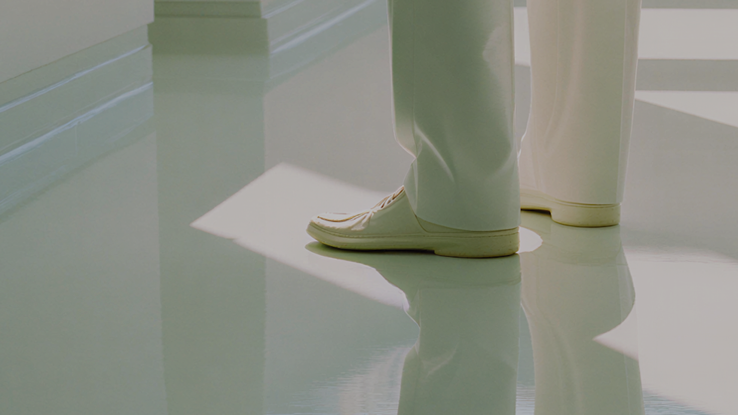 the feet of a person dressed in white standing on a shiny white floor